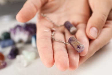 Photo of Woman holding handmade gemstone earrings at table, closeup