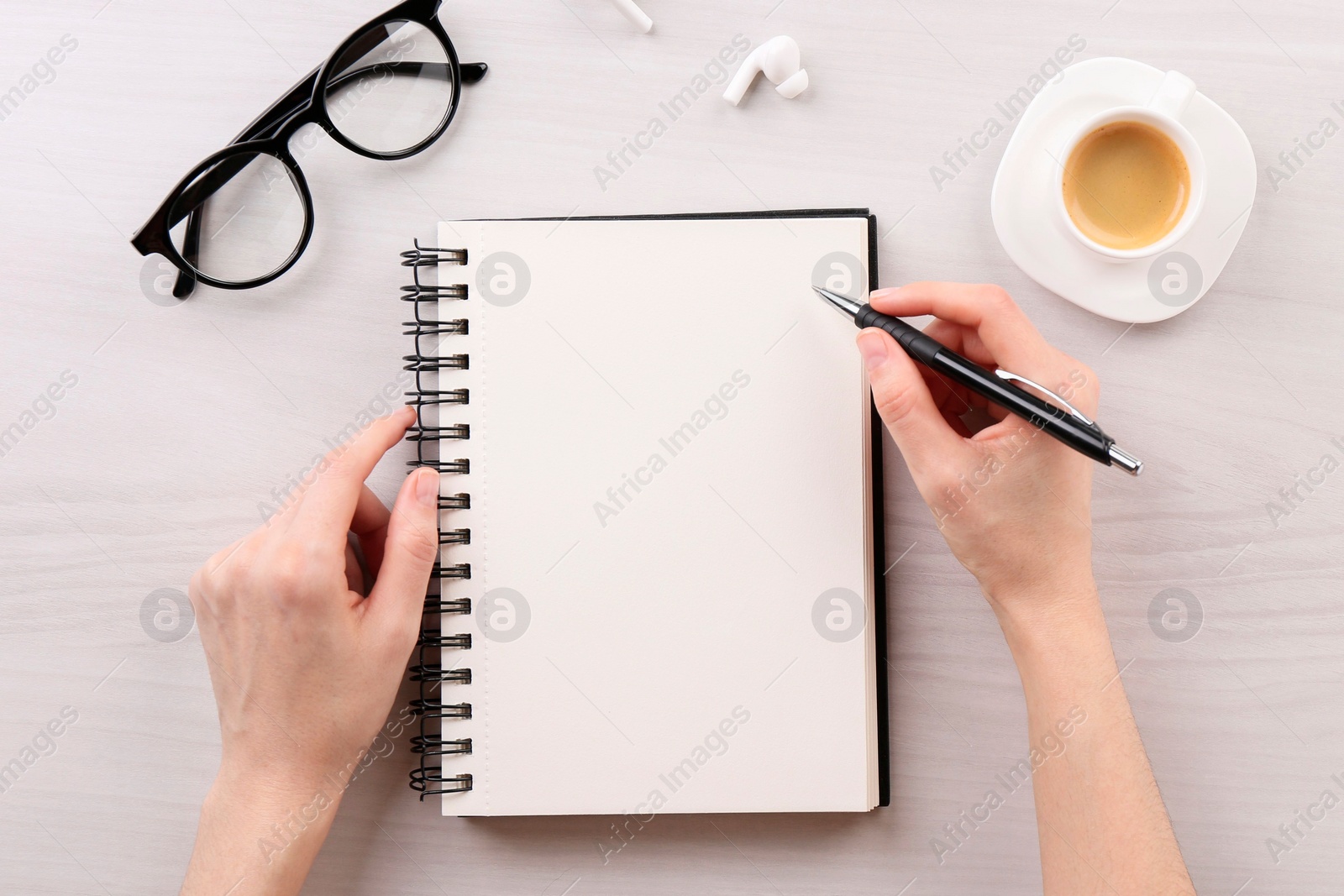 Photo of Woman with notebook and pen at white wooden table, top view. Space for text