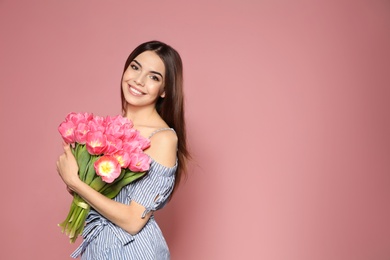 Photo of Portrait of beautiful smiling girl with spring tulips on pink background, space for text. International Women's Day