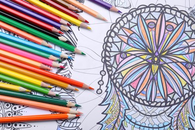 Photo of Pencils on antistress coloring pages, top view