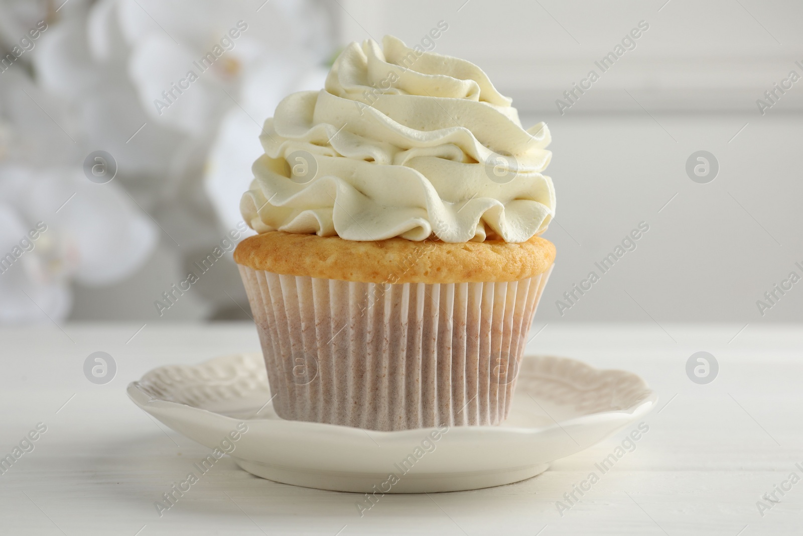 Photo of Tasty vanilla cupcake with cream on white table, closeup