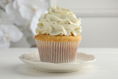 Tasty vanilla cupcake with cream on white table, closeup