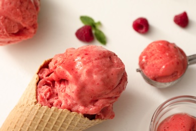 Photo of Delicious pink ice cream in wafer cone on white table, closeup
