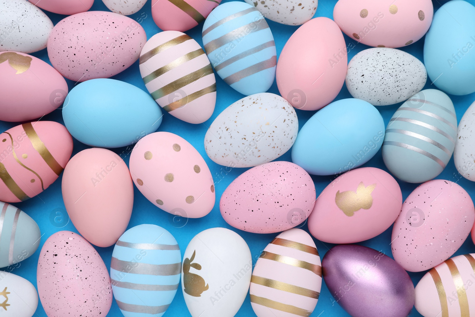 Photo of Many painted Easter eggs on blue background, flat lay