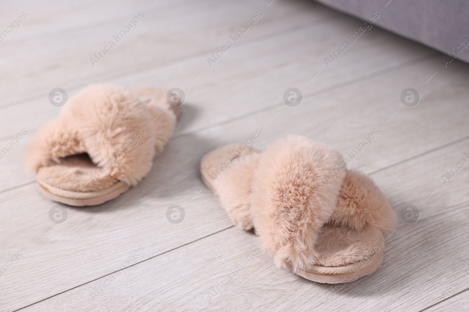 Photo of Beige soft slippers on light wooden floor at home