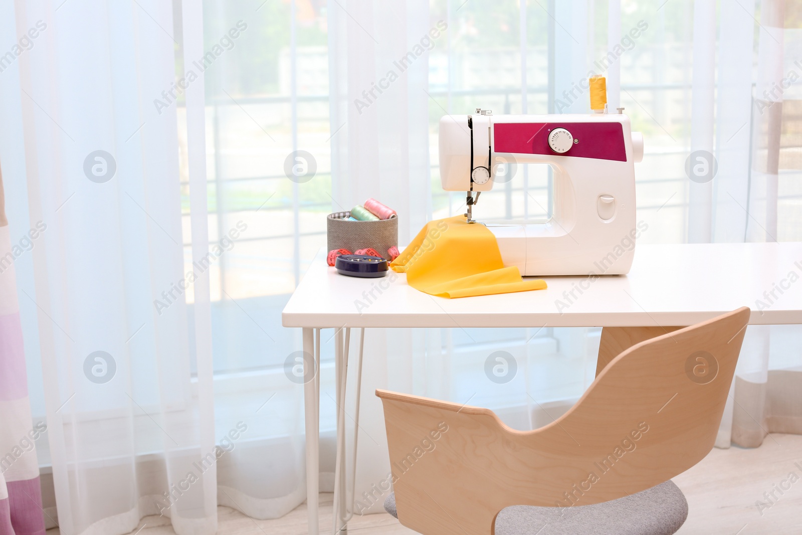 Photo of Modern sewing machine on table near window indoors