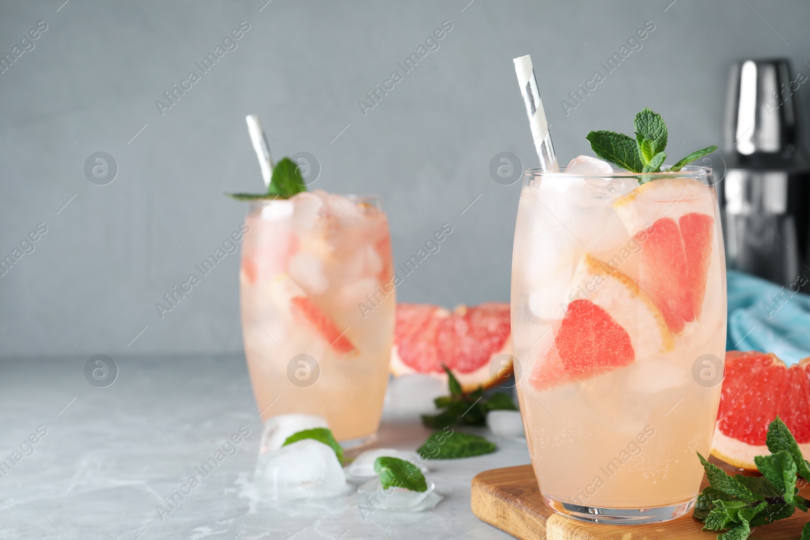 Photo of Glasses of fresh cocktail with grapefruit on grey marble table. Space for text