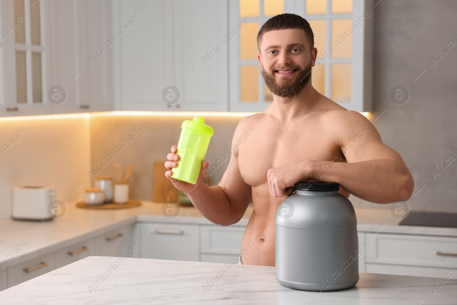 Photo of Young man with shaker of protein and powder at white marble table in kitchen, space for text