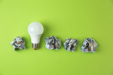 Photo of Flat lay composition with lamp bulb and crumpled money on color background