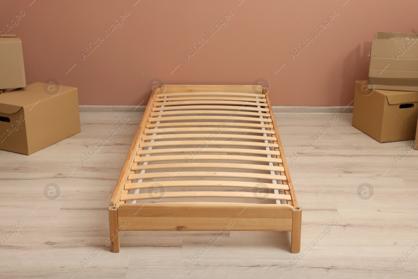 Photo of Wooden bed frame and cardboard boxes on floor in room