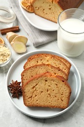 Photo of Slices of delicious gingerbread cake served with milk on light grey table