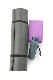 Grey exercise mat, yoga block and bottle of water isolated on white, top view