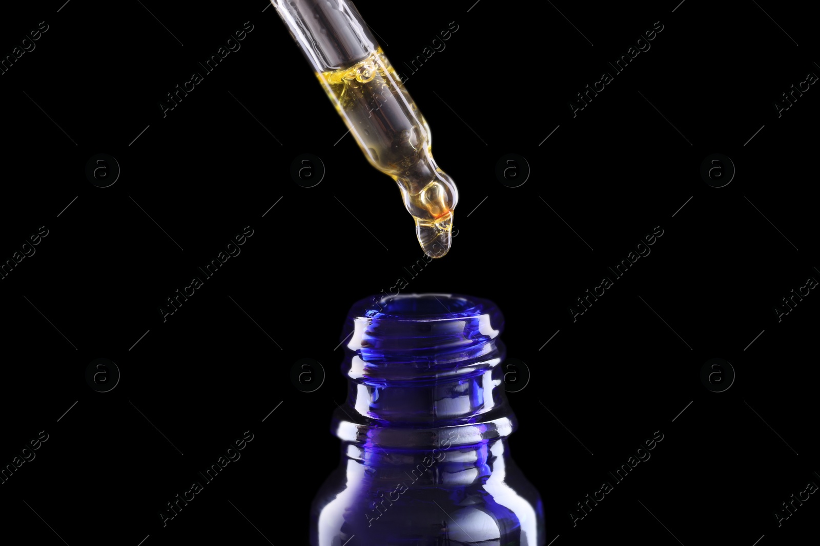 Photo of Dripping tincture from pipette into bottle on dark background, closeup