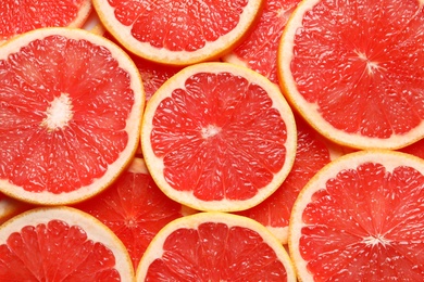 Juicy grapefruit slices as background, top view. Citrus fruit