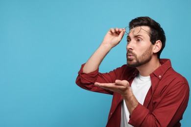 Photo of Handsome man blowing kiss on light blue background. Space for text