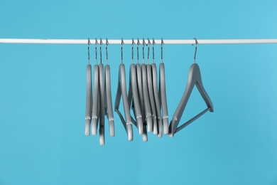 Metal rack with clothes hangers on color background