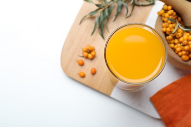 Top view of sea buckthorn juice on white table, space for text