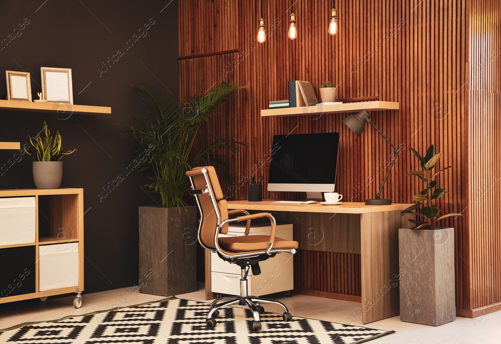 Photo of Comfortable workplace with computer near wooden wall in stylish room interior. Home office design