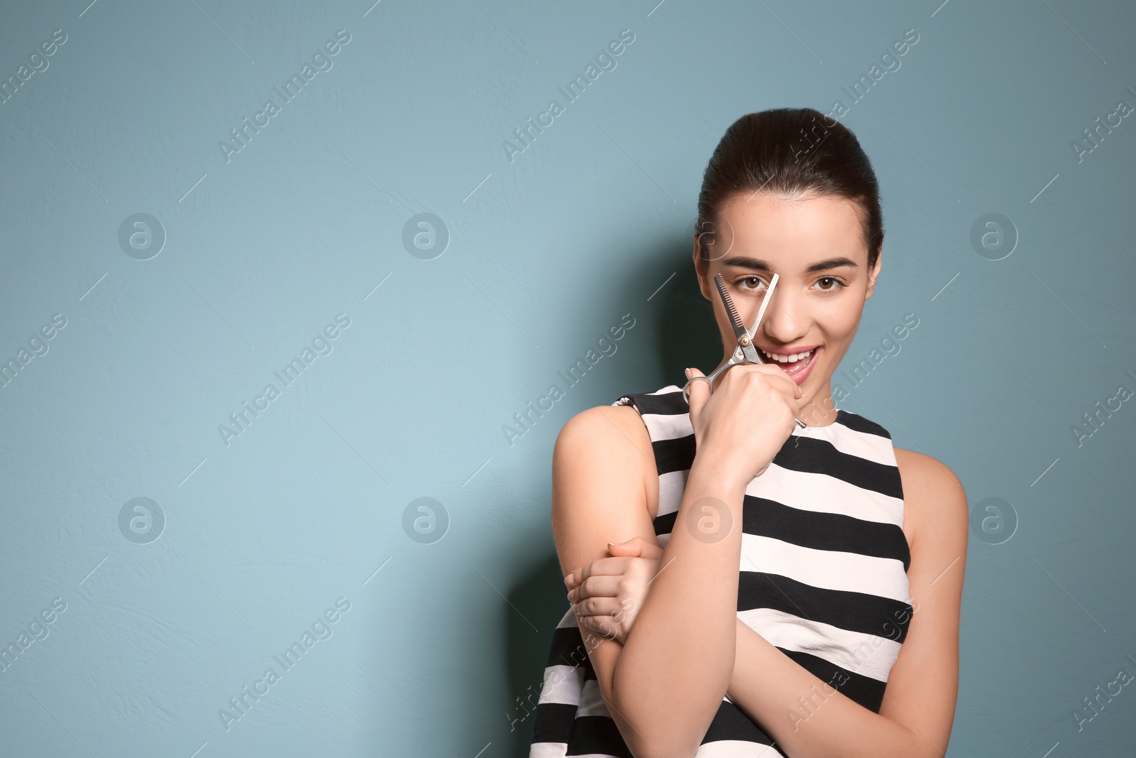 Photo of Professional hairdresser with scissors on color background