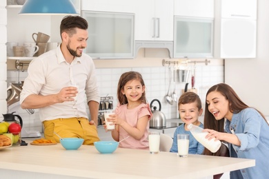 Photo of Happy family having breakfast with milk in kitchen