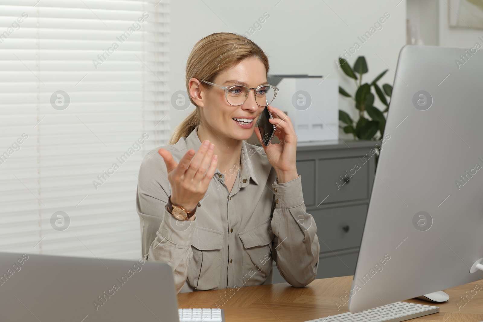 Photo of Professional accountant talking on phone while working at wooden desk in office