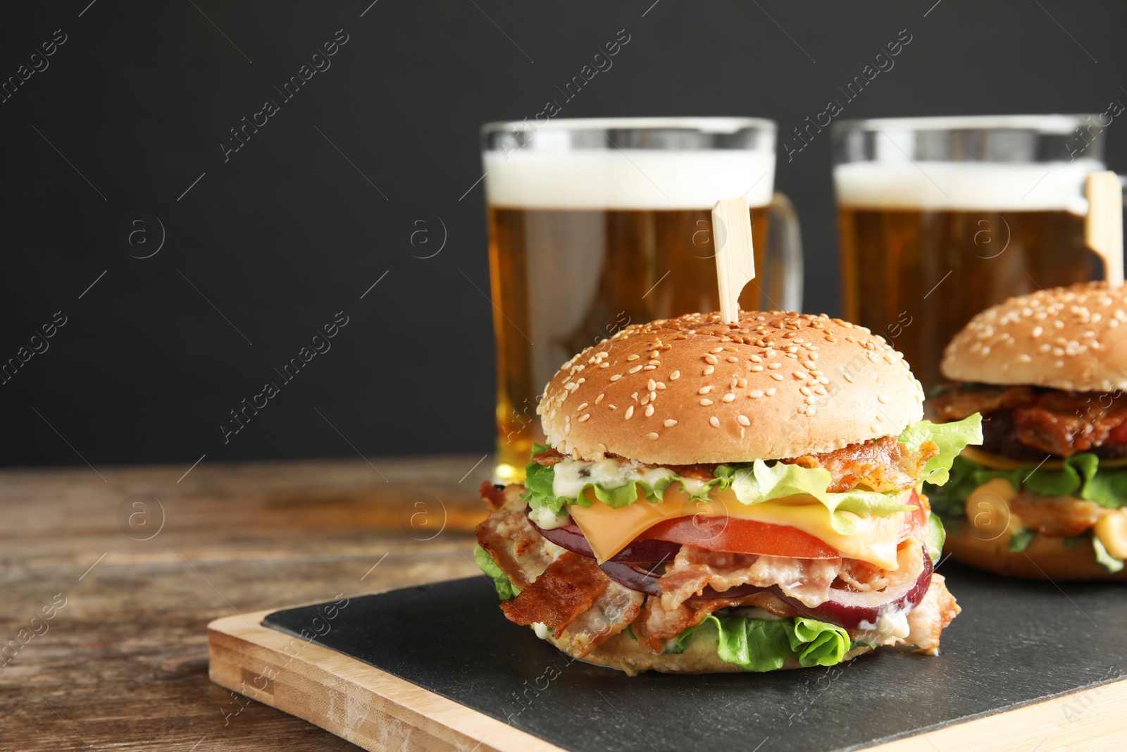 Photo of Tasty burger with bacon served on table. Space for text