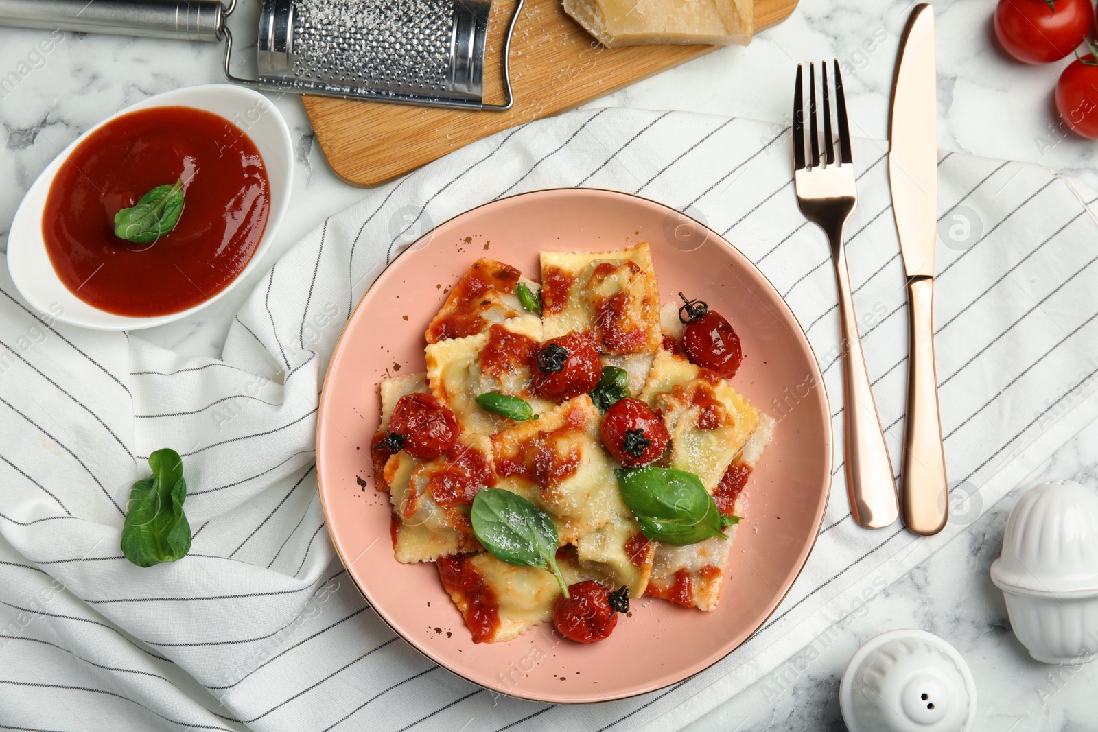 Photo of Tasty ravioli with tomato sauce served on white marble table, flat lay
