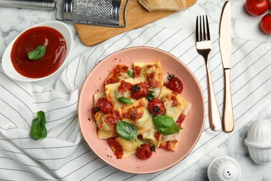 Tasty ravioli with tomato sauce served on white marble table, flat lay