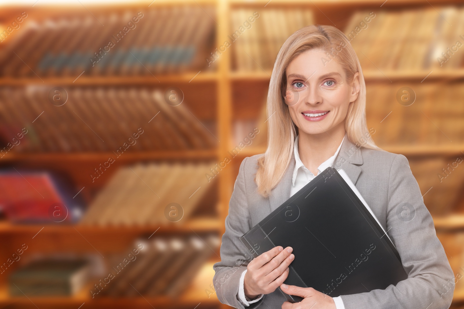Image of Lawyer, consultant, business owner. Confident woman with file folder smiling indoors, space for text