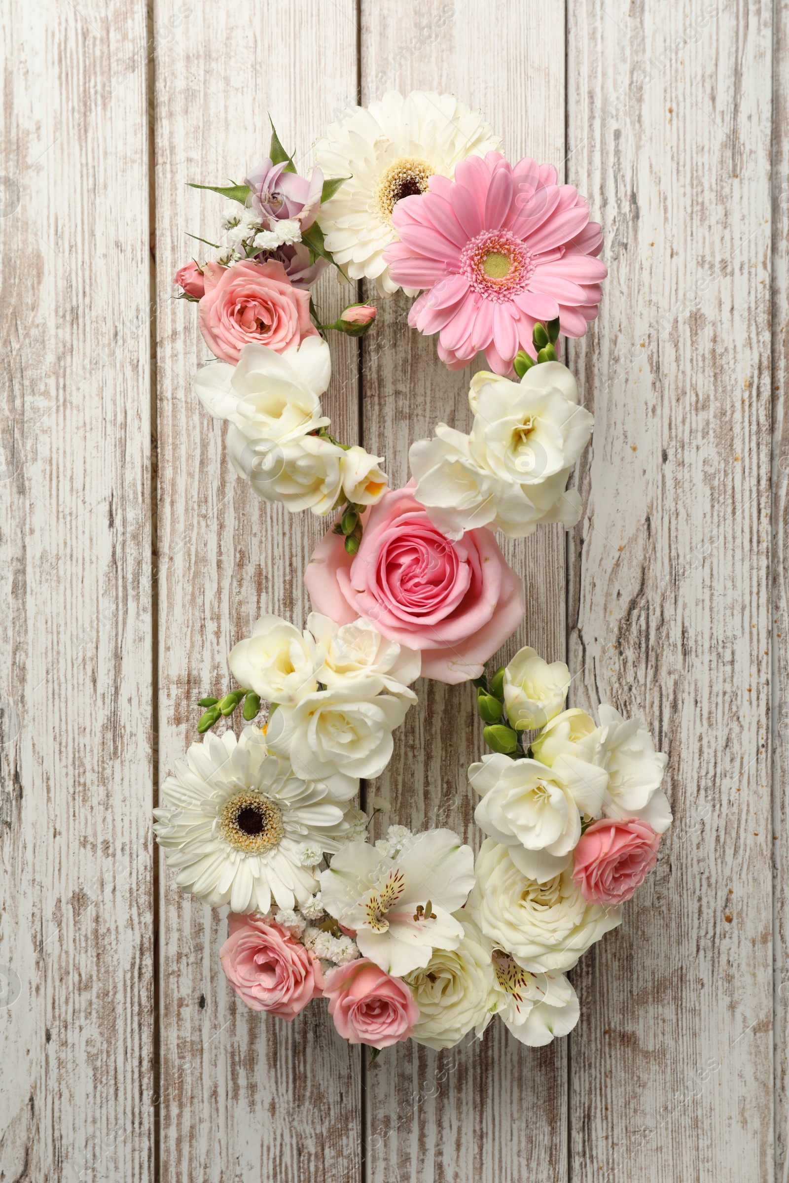 Photo of Number 8 made of beautiful flowers on white wooden table, flat lay. International Women's day