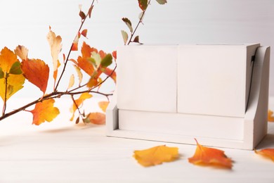 Photo of Thanksgiving day, holiday celebrated every fourth Thursday in November. Block calendar and branch with orange leaves on white wooden table