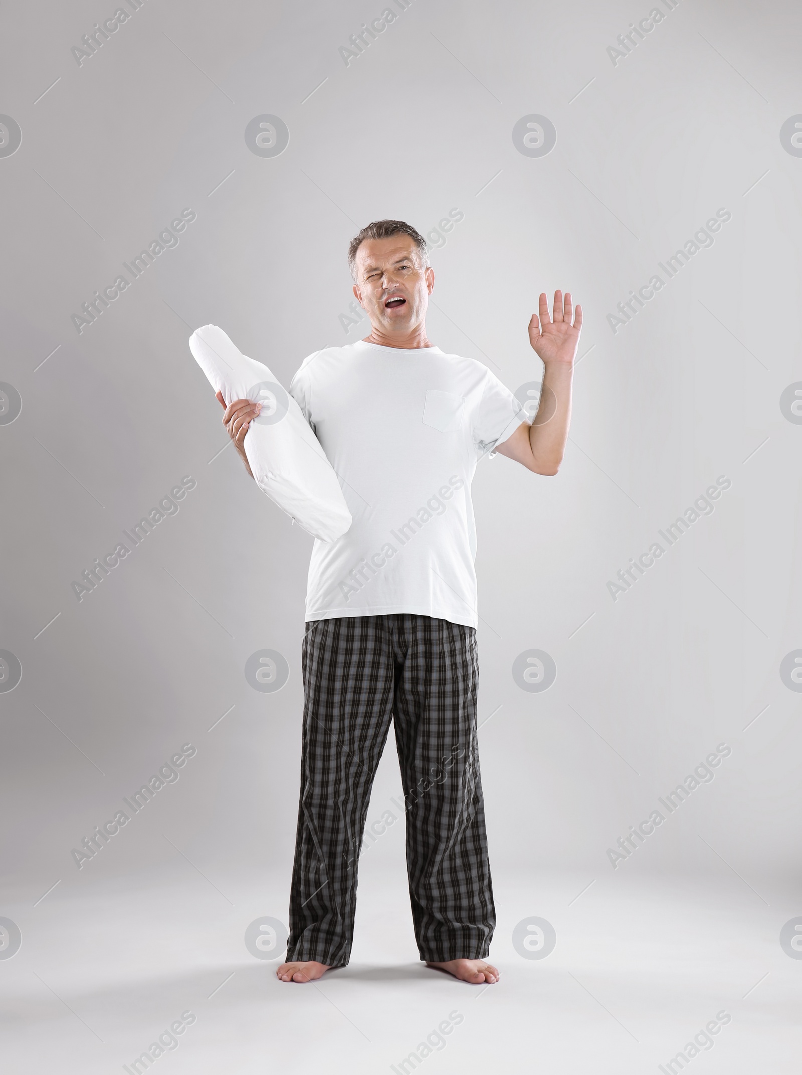 Photo of Man holding soft pillow on light background