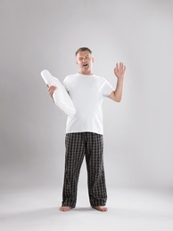 Man holding soft pillow on light background