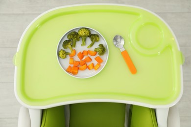 Photo of Baby high chair with healthy food, top view