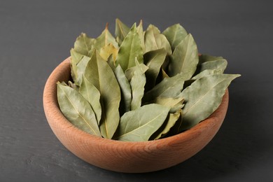 Photo of Aromatic bay leaves in wooden bowl on gray table