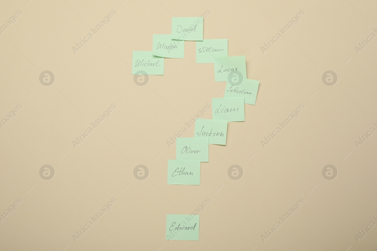 Photo of Choosing baby`s name. Paper stickers with different names in shape of question mark on beige background, top view
