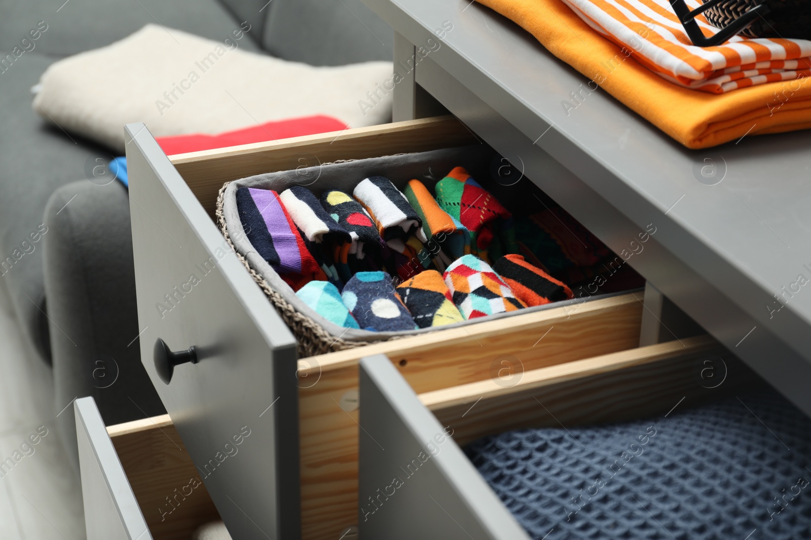 Photo of Chest of drawers with different folded clothes indoors, closeup