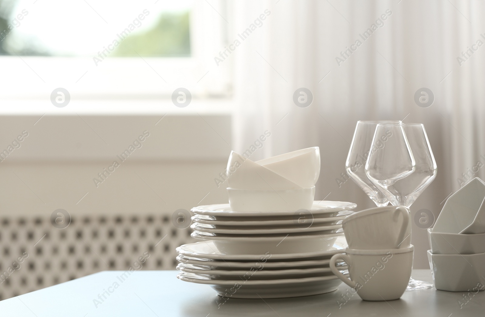 Photo of Set of clean dishware and wineglasses on table indoors. Space for text