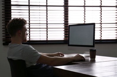 Photo of Lonely man sitting at computer with empty screen indoors