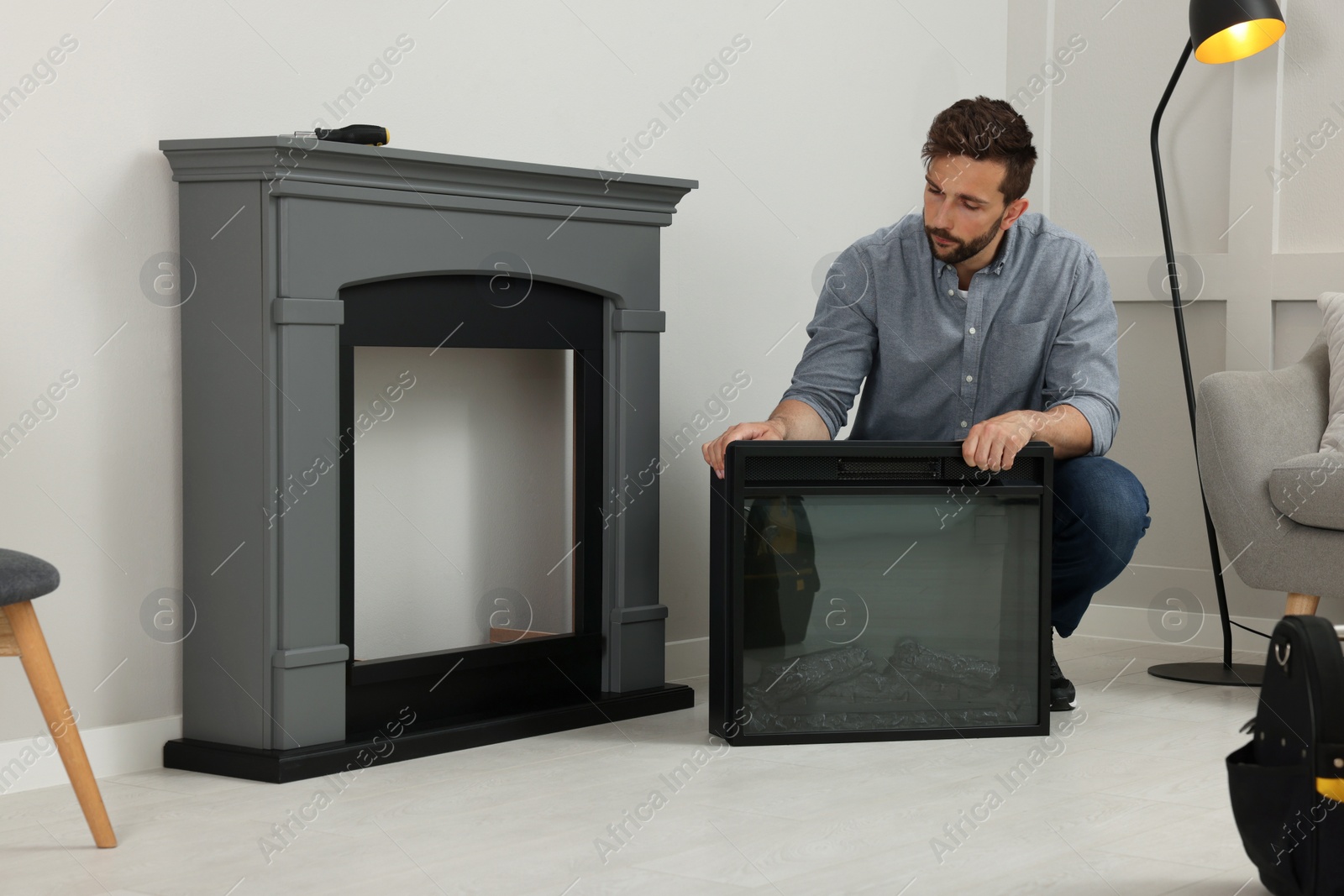 Photo of Man installing electric fireplace near wall in room