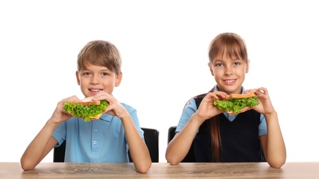 Happy children eating healthy food at school table on white background