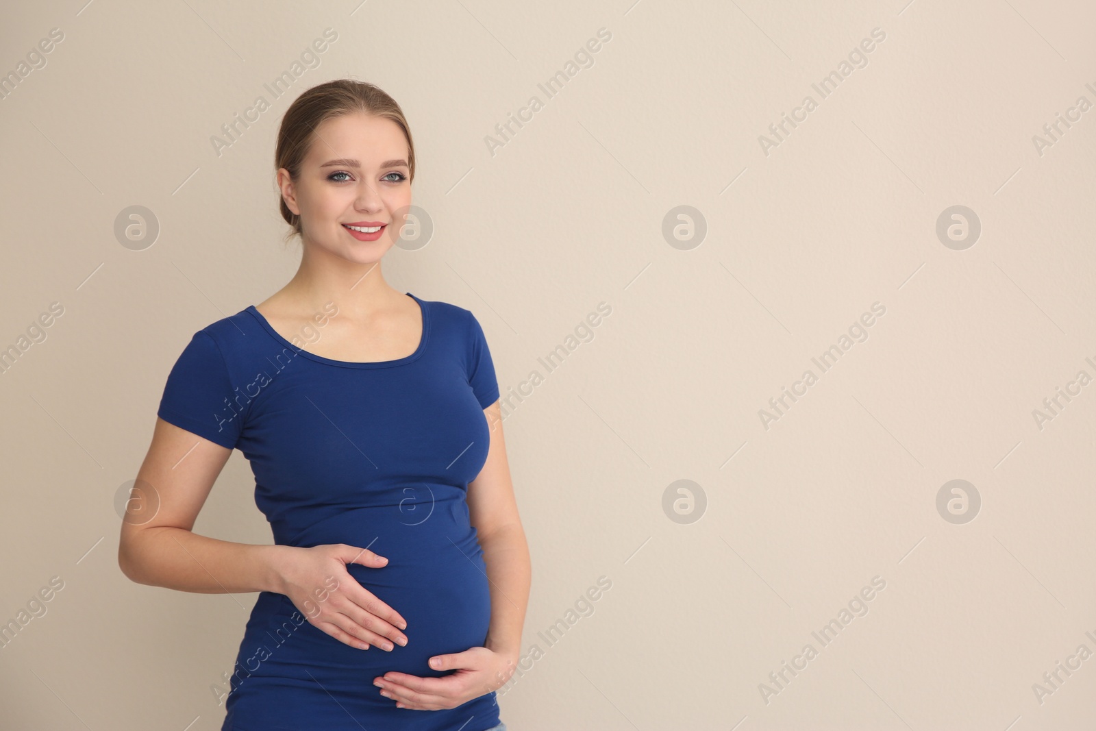 Photo of Young pregnant woman on beige background. Space for text