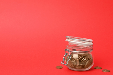 Photo of Glass jar with coins on red background, space for text