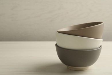 Stylish empty ceramic bowls on white wooden table, space for text. Cooking utensils