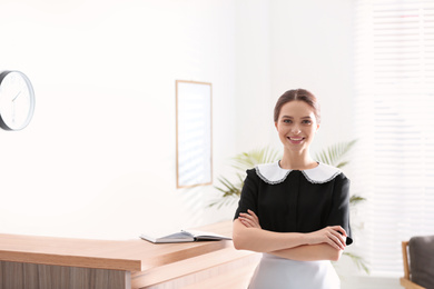 Photo of Young chambermaid near reception in hotel. Space for text