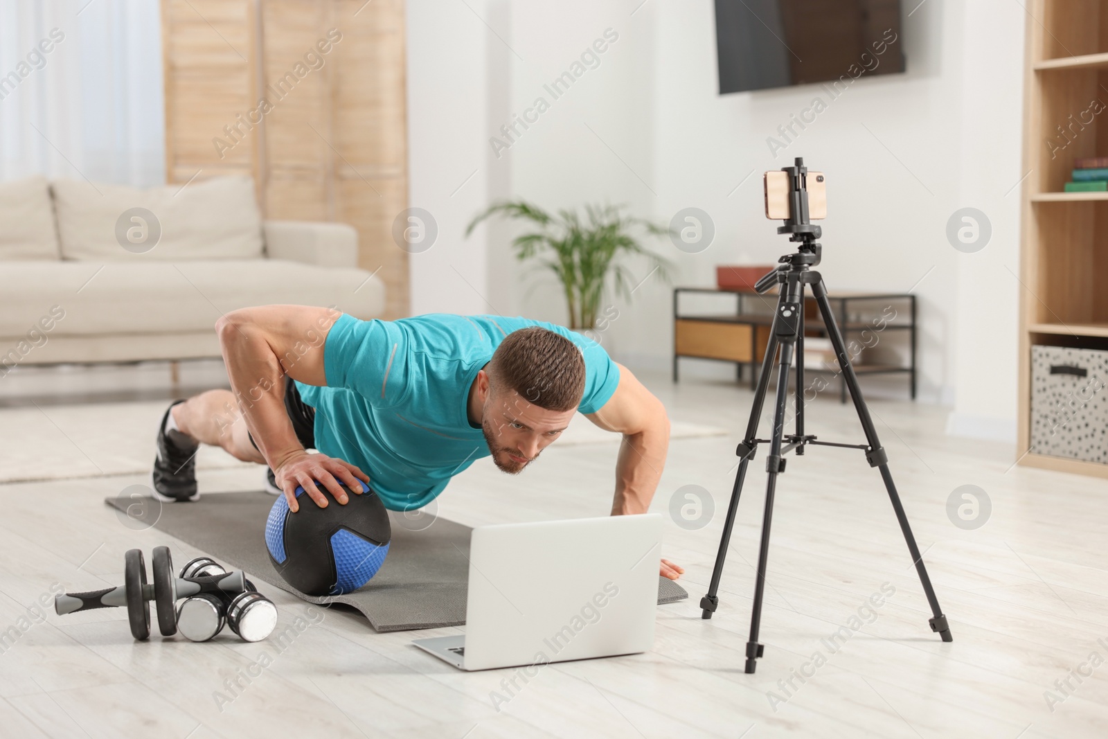 Photo of Trainer with ball streaming online workout on phone at home