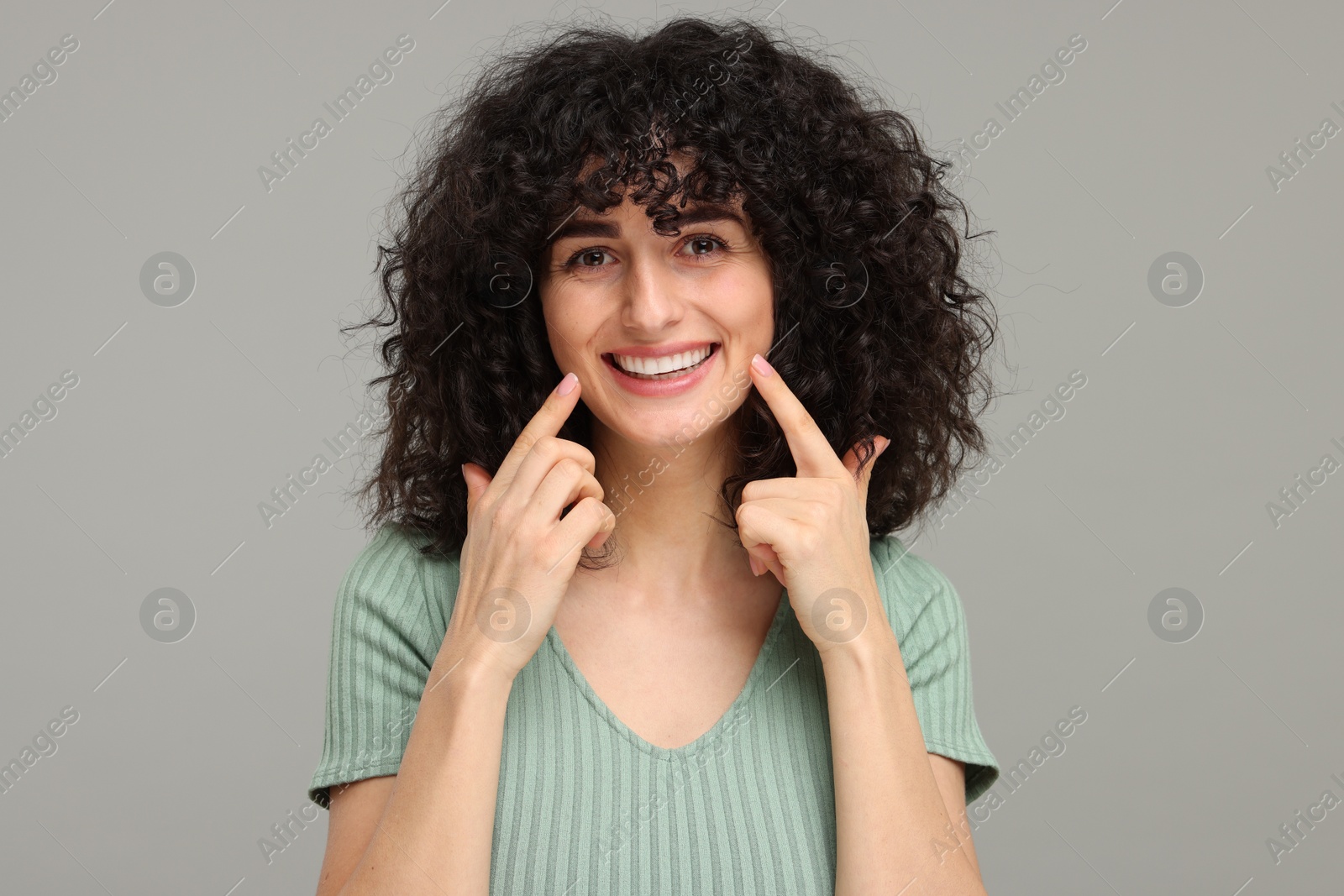 Photo of Young woman showing her teeth with whitening strip on grey background