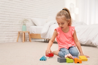 Photo of Cute child playing with building blocks on floor at home