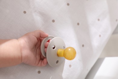 Photo of Little baby with pacifier in bed, closeup