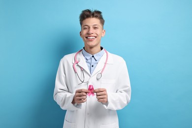 Photo of Mammologist with pink ribbon on light blue background. Breast cancer awareness